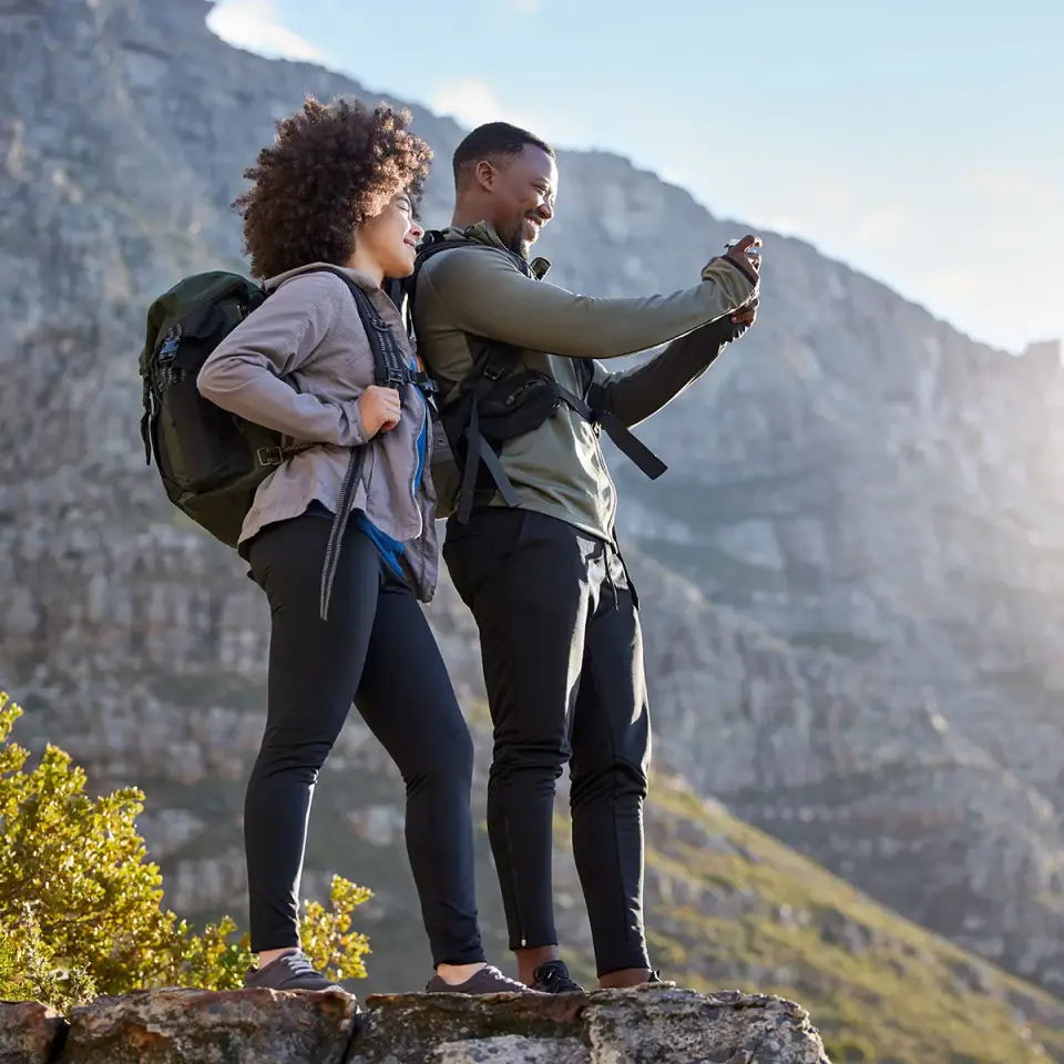 A man takes a selfie of he and a woman while standing outside during a hike. They are being active after medical detox at Sheridan Grove Recovery.