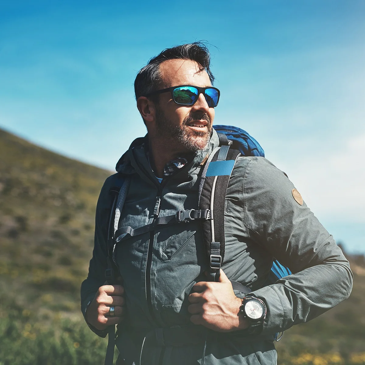 A man in a backpack is on an outdoor adventure. He recently participated in medication-assisted treatment at Sheridan Grove Recovery and is feeling free and happy.