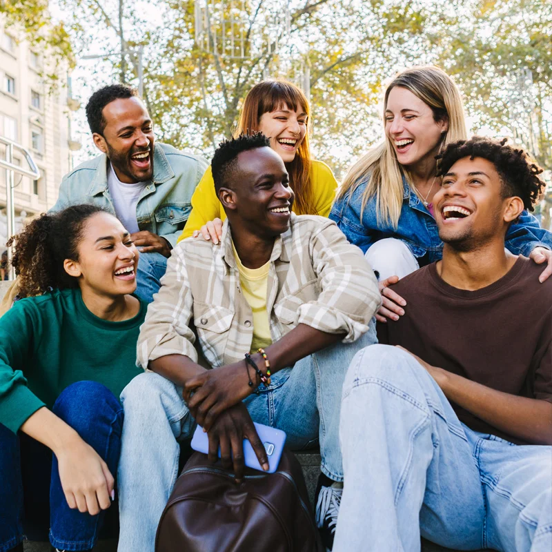 A group of young people sit closely together, laughing. They are all thriving after treatment at Sheridan Grove Recovery.