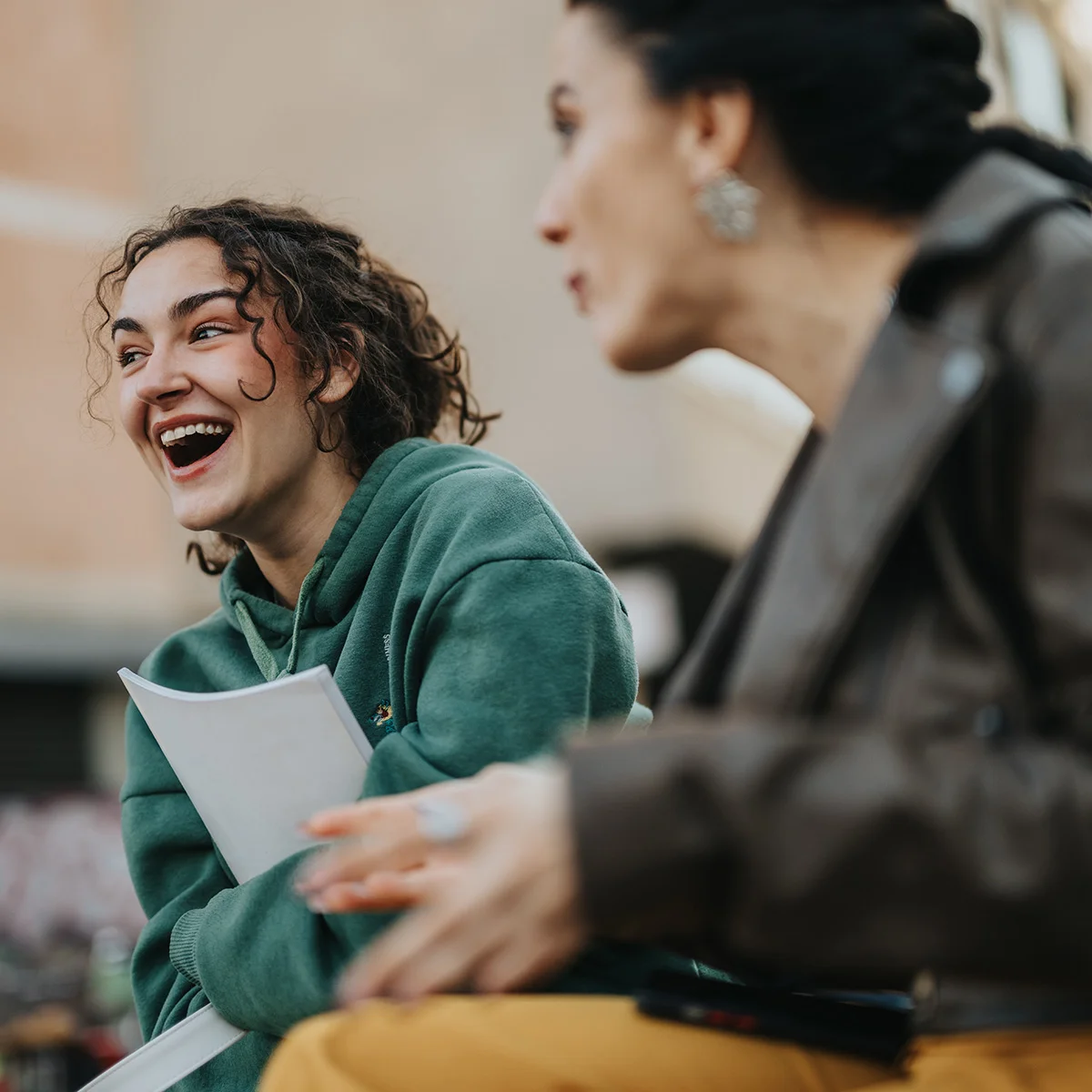 A young woman laughs while sitting next to her therapist. She is enjoying her time in therapy programs at Sheridan Grove Recovery.
