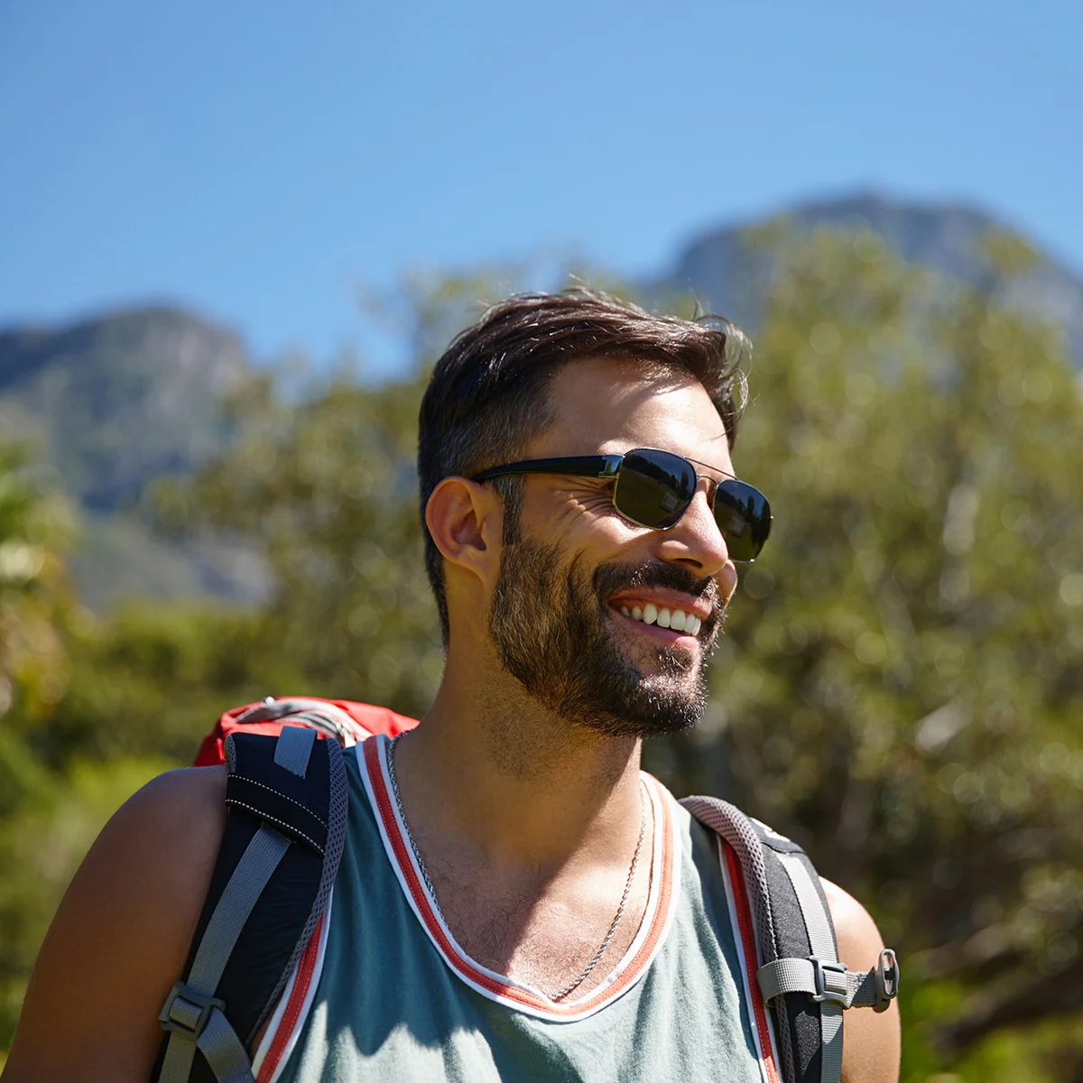 A man is smiling while backpacking outside. He is feeling free after the treatment programs at Sheridan Grove Recovery.