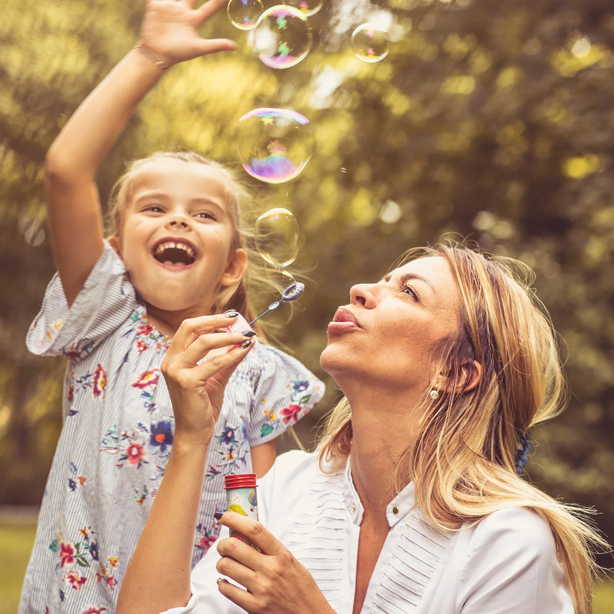 A woman is blowing bubbles with her daughter. She is able to be an active mom after treatment programs at Sheridan Grove Recovery.